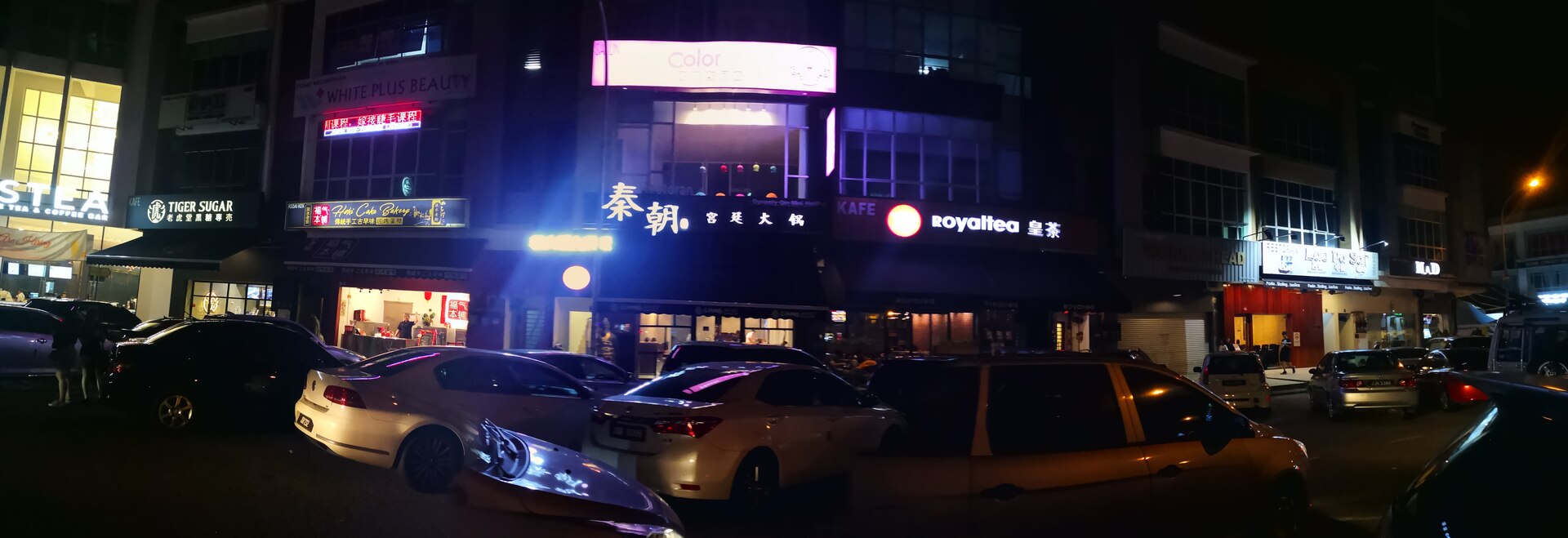 A street of lit-up boba tea shops at night