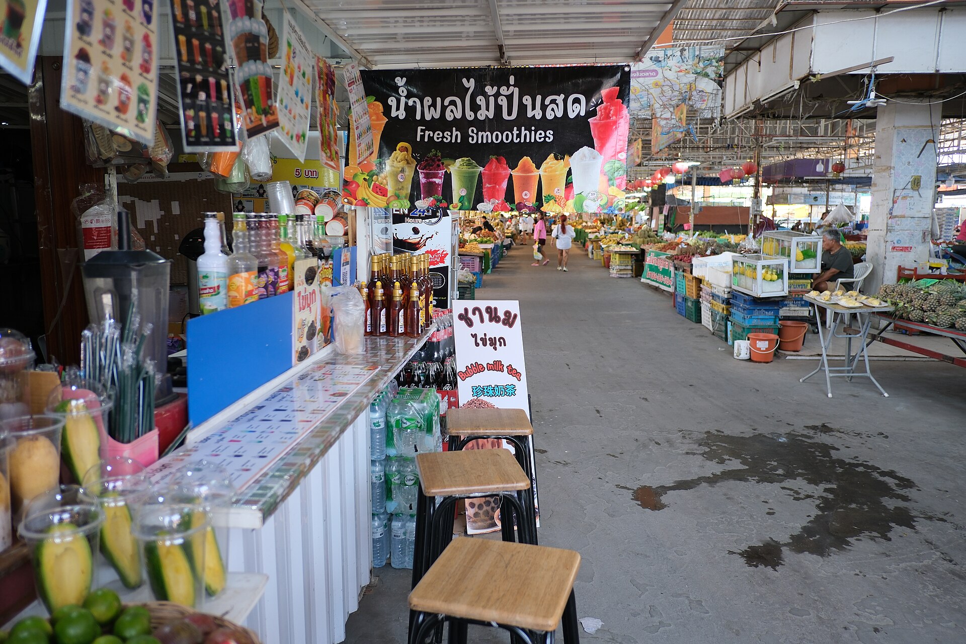 A market aisle lined with fresh drink and fruit stalls