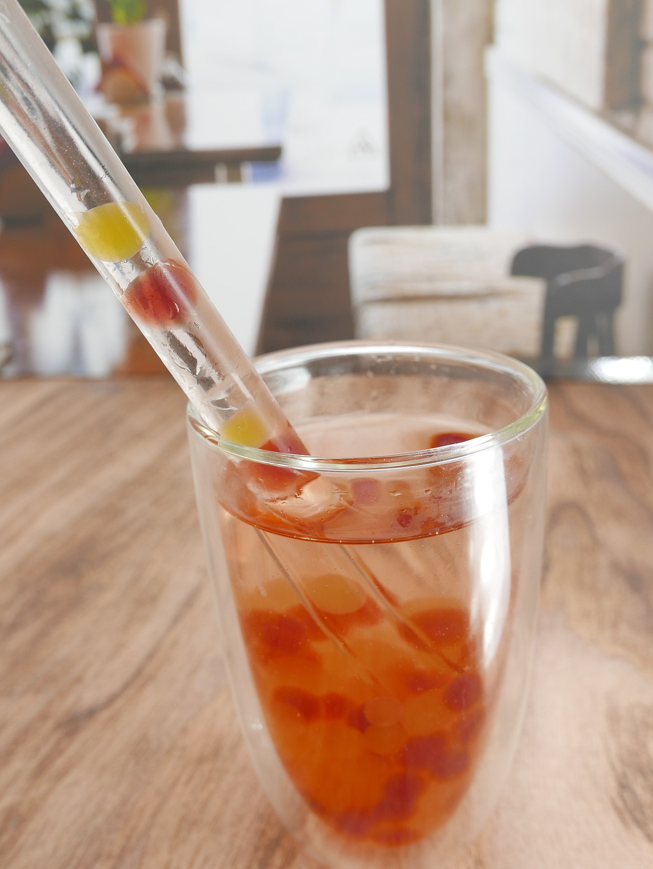 A glass of amber fruit tea with two straws