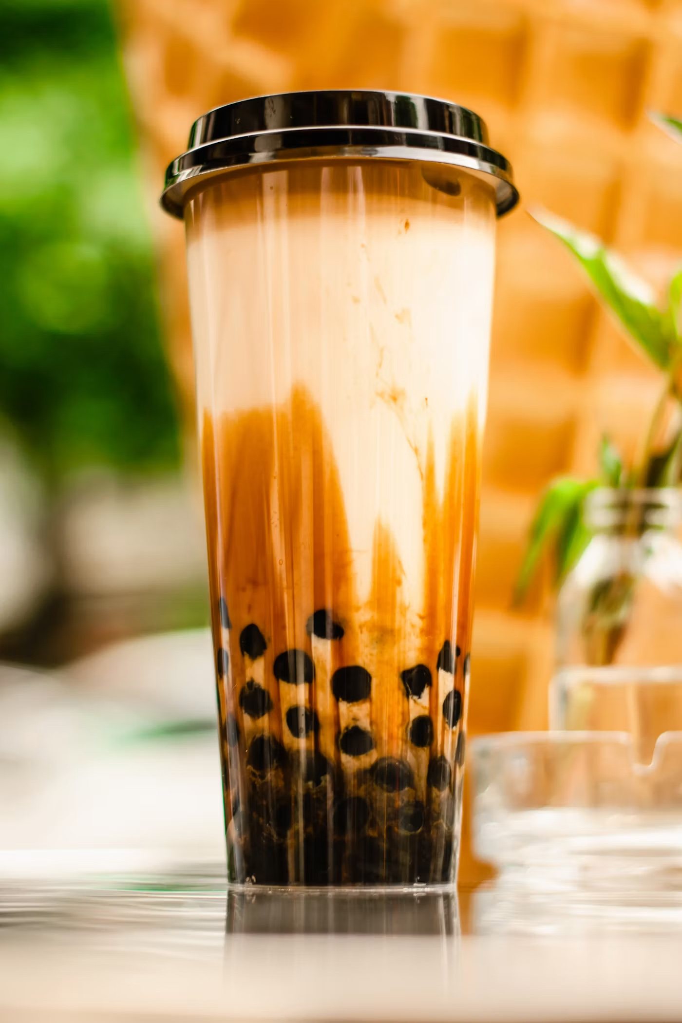 Tiger milk tea with brown sugar streaked down the cup and boba at the bottom
