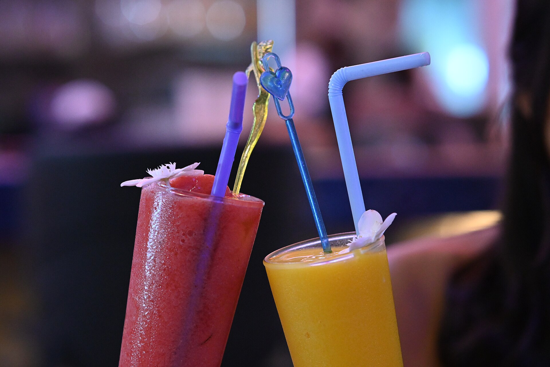 Two tropical smoothies topped with stirrers and straws